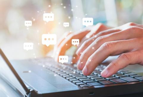 Ihmisen kädet näppäimistöllä. Kirjoittaa ja vastaanottaa viestejä, ilmassa puhekuplia.